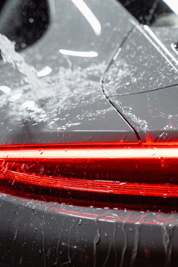 creative Close-up of a vehicles taillight being washed, featuring water and soap suds for a clean and shiny finish.